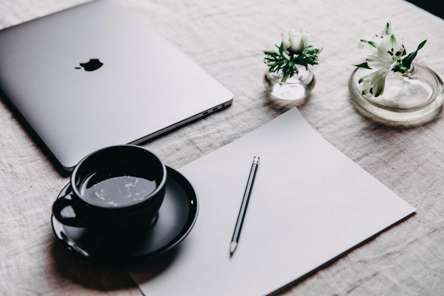 Skrivbord med kaffe, anteckningsblock och penna