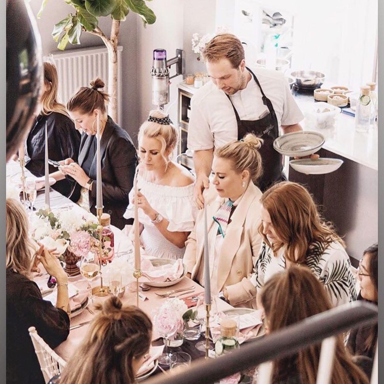 Middagsbjudning där kock serverar gäster runt dukat bord